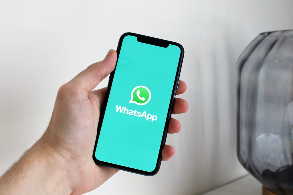 Ekranında WhatsApp logosu bulunan bir cep telefonu tutan bir kişi